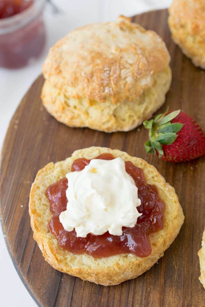 The bottom half of a scone topped with jam and clotted cream