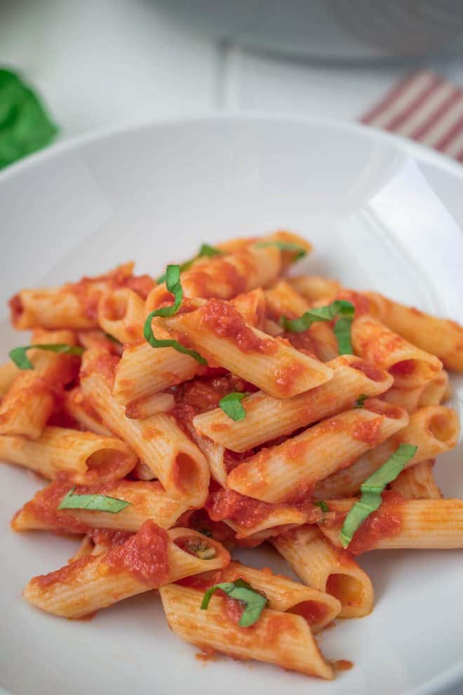 A closeup showing the tomato sauce on the pasta and fresh basil