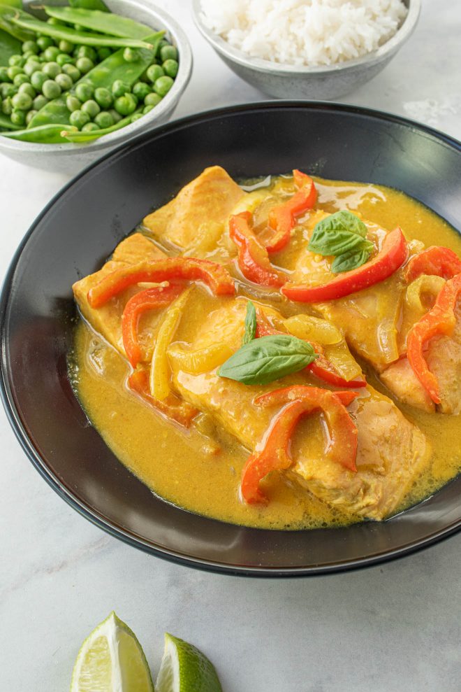 A closeup of the salmon in curry topped with red pepper and basil