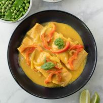 A view from above of 2 salmon filets in a bowl in curry sauce