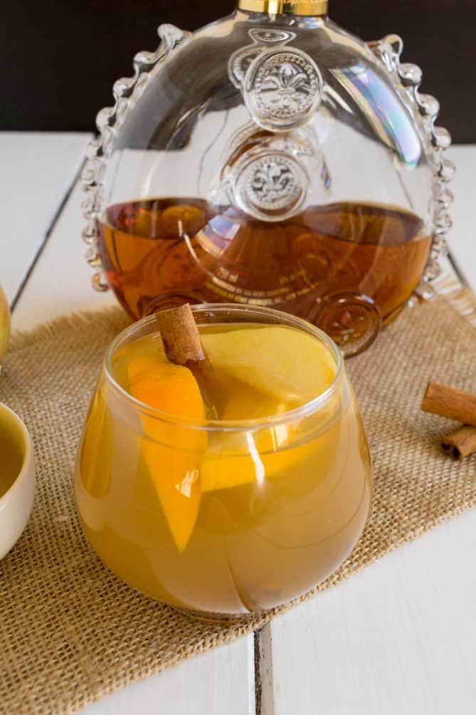 Cognac in a decanter that was used to make an apple cider cocktail served in a glass