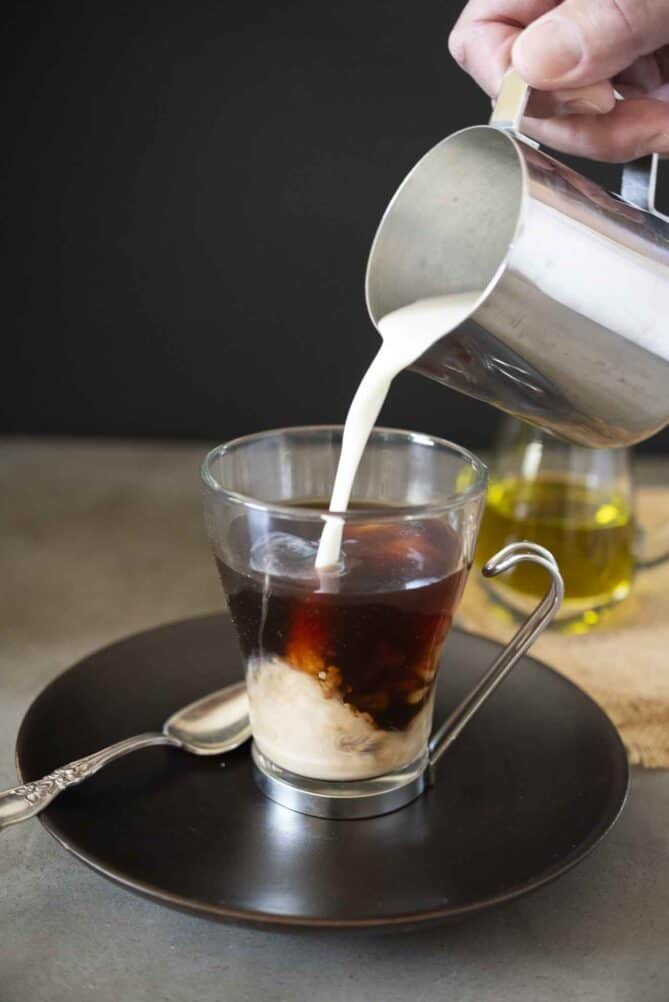 Pouring milk into a cup of coffee