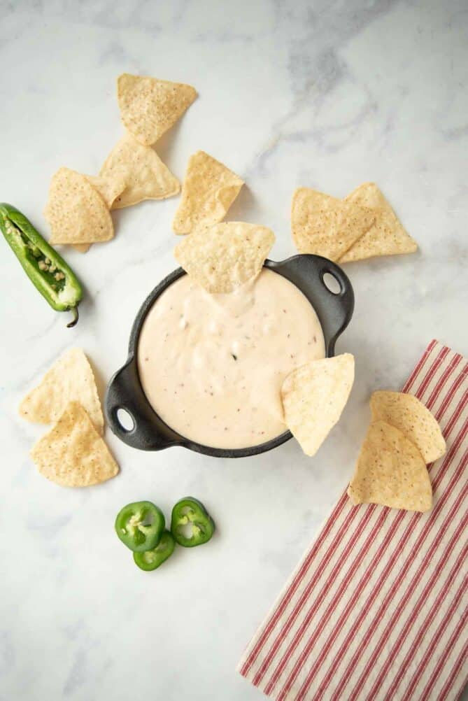 Queso viewed from above with tortilla chips and peppers