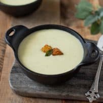 A bowl of cornbread, sage and onion soup on a serving platter with a spoon