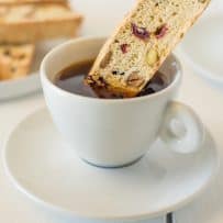 Dipping a cranberry orange pistachio biscotti into a cup of coffee
