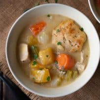 A bowl of creamy chicken stew with a sage and chive dumpling