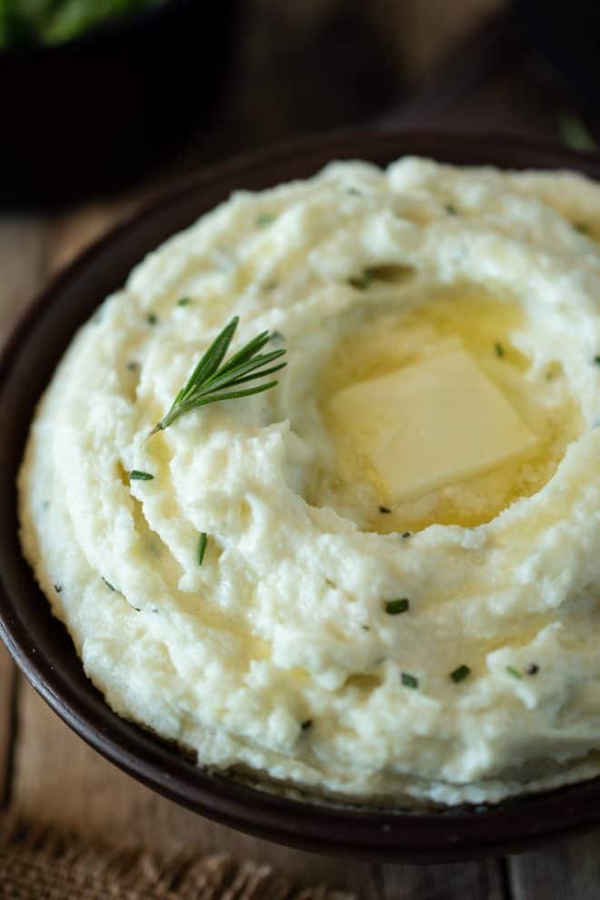 A closeup of the mash showing butter melting on the top with flecks of rosemary.