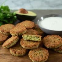 Brown and crispy falafel on a serving board with yogurt tahini sauce