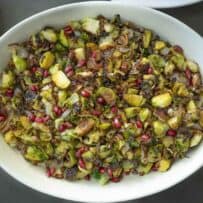 Vibrant green Brussels sprouts in a serving dish garnished with red pomegranate seeds