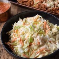 Crunchy vegetable coleslaw with vibrant orange carrot shreds and green scallions in a bowl