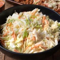A black bowl filled with crunchy vegetable coleslaw