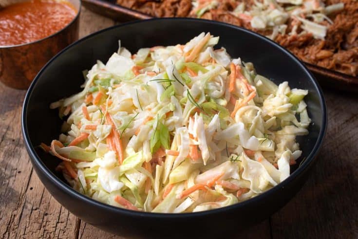 A black bowl filled with crunchy vegetable coleslaw