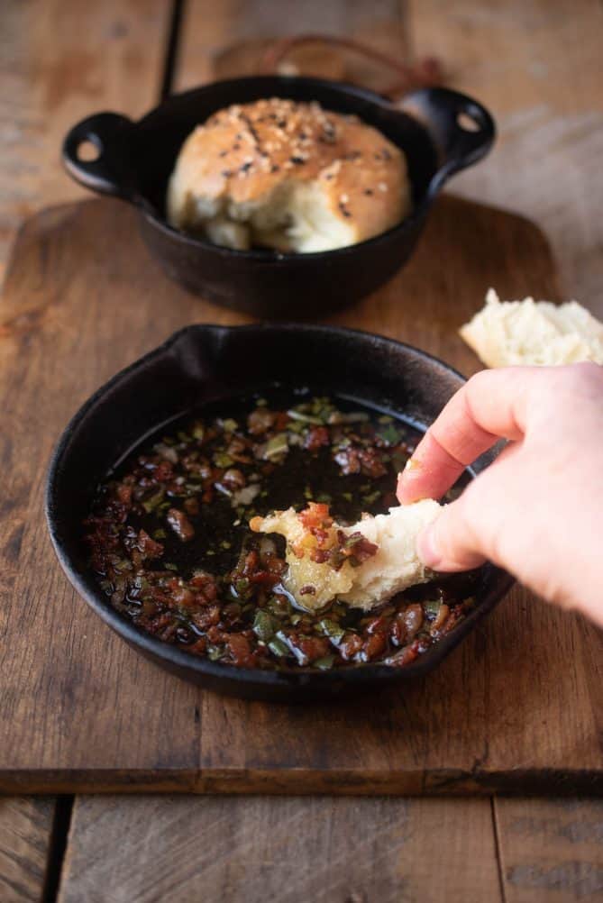 Dipping a piece of bread roll into bacon sage butter