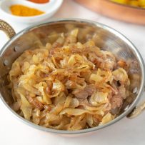 A copper bowl full of curry caramelized onions
