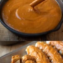 A cast iron bow full of curry ketchup and cut up sausages with the sauce on top