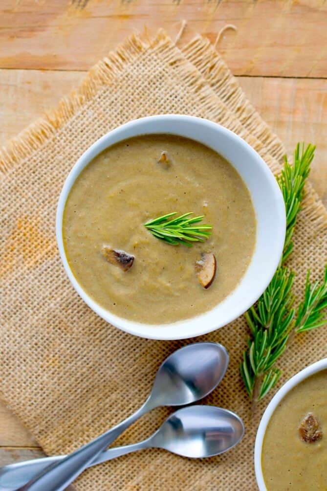 A bowl of mushroom soup with spoons viewed from overhead