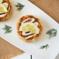 Crab cake viewed from overhead topped with sauce and a lemon slice