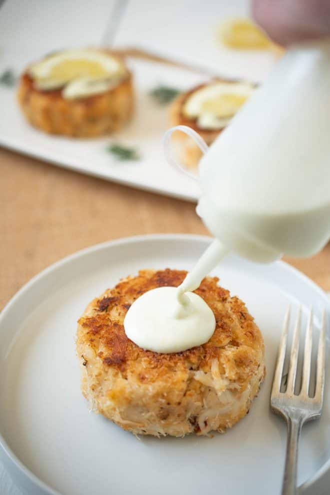 Squeezing lemon scallion sauce onto a crab cake