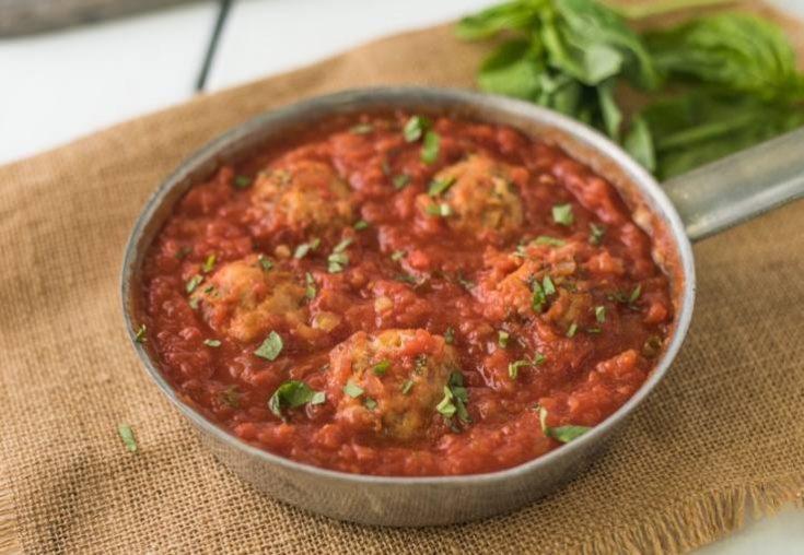 A pan of easy chicken meatballs in marinara sauce garnished with fresh basil
