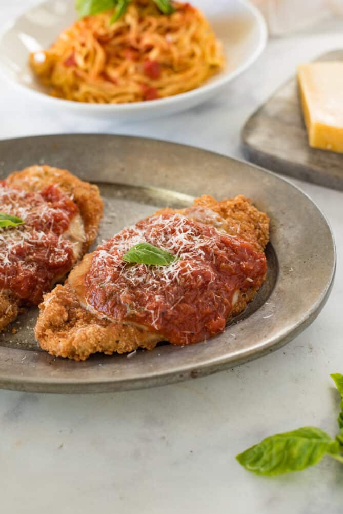 Crispy breaded chicken topped with tomato sauce and cheese on a pewter plate