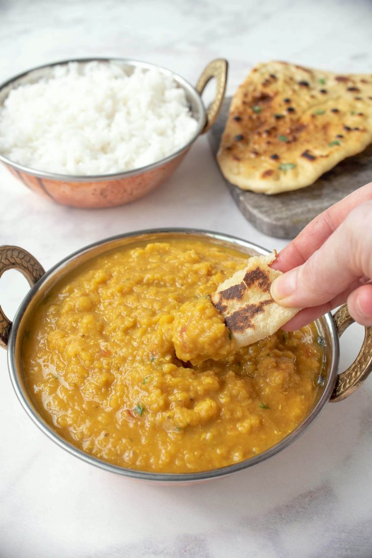 Dipping a piece of naan in lentil dal