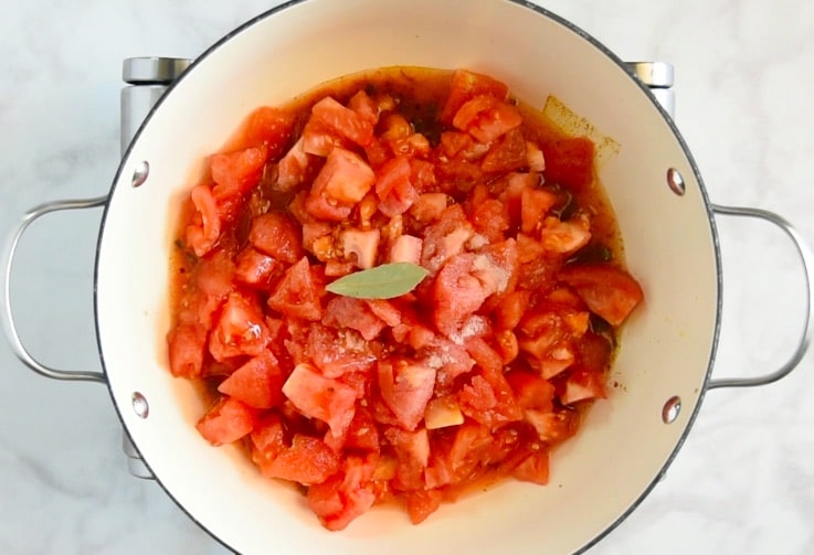 Tomatoes are cooked in a pan with garlic, chili and spices