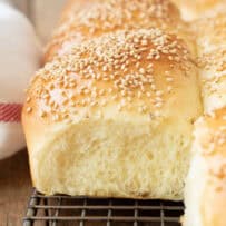 A closeup of a soft and fluffy bread roll topped with sesame seeds
