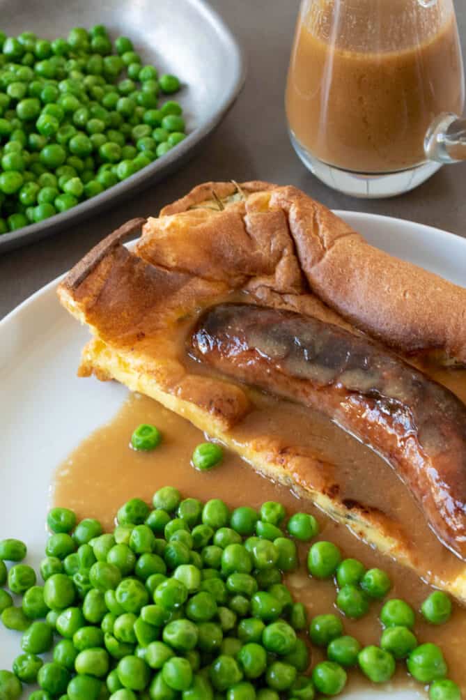 A closeup of a sausage cooked in batter with gravy
