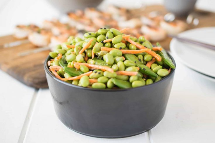 Edamame and snap peas piled high in a black bowl