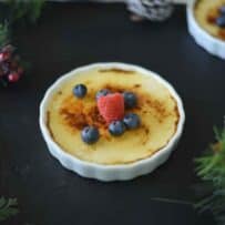 A ramekin filled with eggnog creme brûlée, raspberry and blueberries