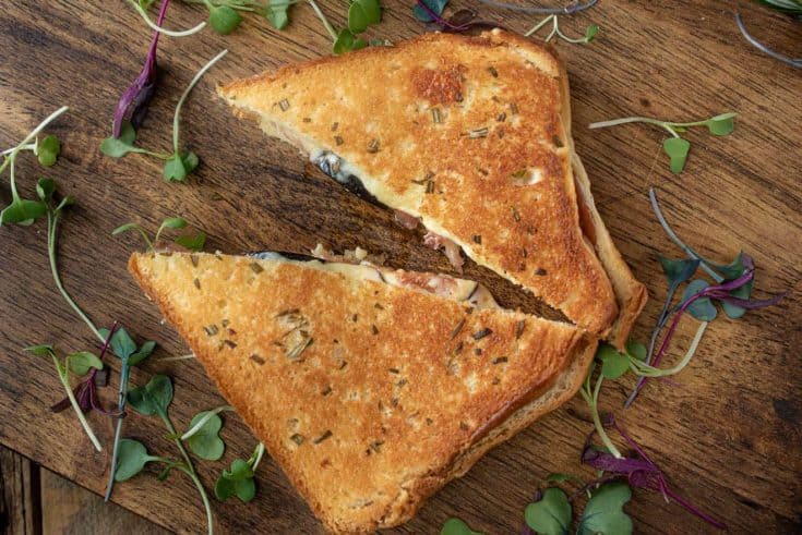 Fig and prosciutto grilled cheese cut in half garnished with micro greens