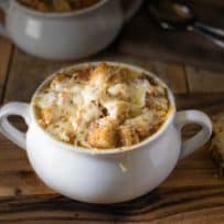 French onion soup in a white bowl with a side of cheese toast
