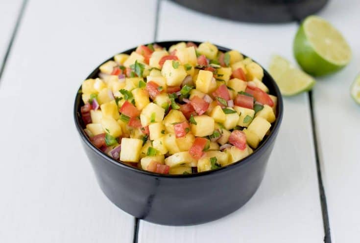 A black bowl filled with fresh pineapple salsa