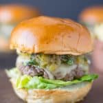 The burger from the side showing the melted cheese, chiles and lettuce