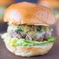 The burger from the side showing the melted cheese, chiles and lettuce