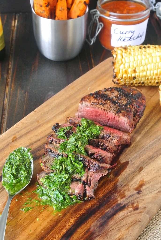 Perfectly grilled filet mignon sliced on a board with mint and parsley