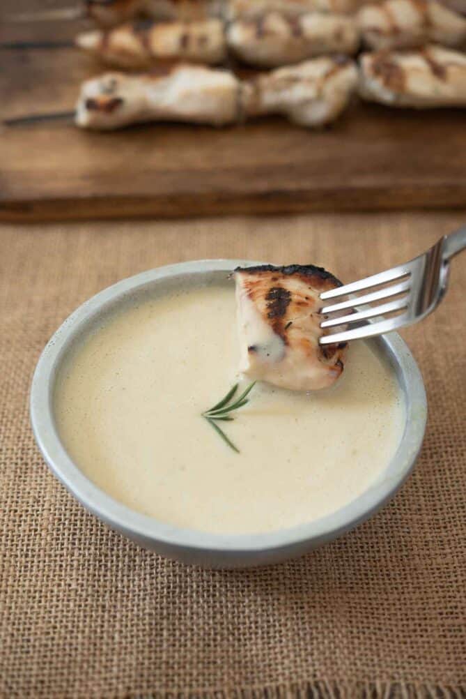 Dipping a piece of grilled chicken into mustard sauce