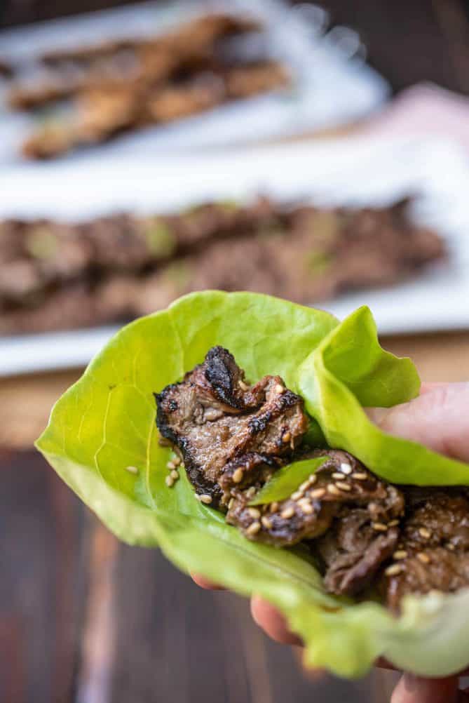 Pieces of grilled beef inside a lettuce leaf with sesame seeds and sliced scallion
