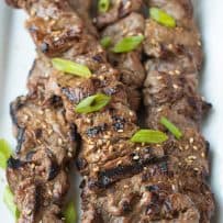 Perfectly grilled beef on skewers lined up on a white plate