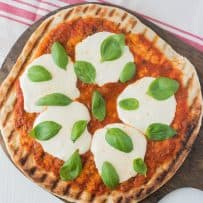 Uncut, viewed from overhead on a pizza board with a pizza cutter