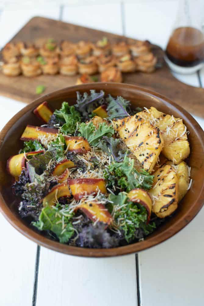 Grilled pineapple coconut salad in a wooden bowl with grilled shrimp in the background