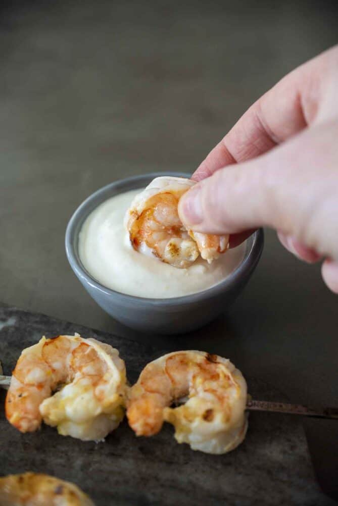 A pink, cooked shrimp dipped into ginger lemon sauce