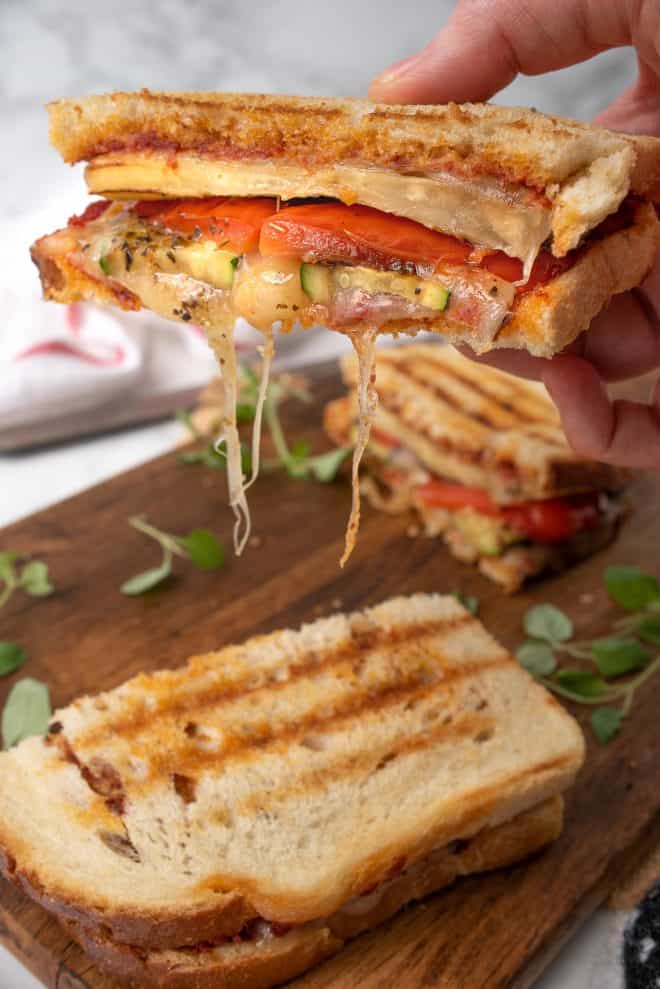 Holding a half of the panini with lots of melted cheese strings