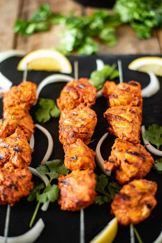 3 skewers of chicken tandoori with onion, lemon and cilantro