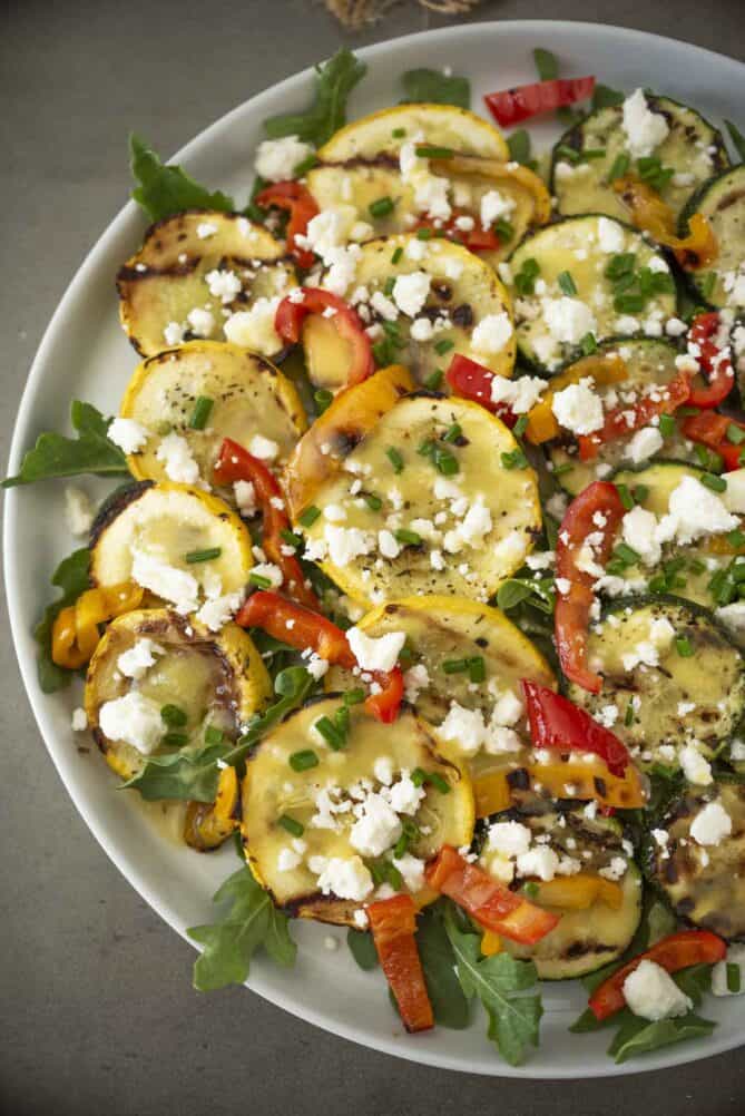Grilled squash slices topped with crumbled feta cheese, peppers and chopped chives