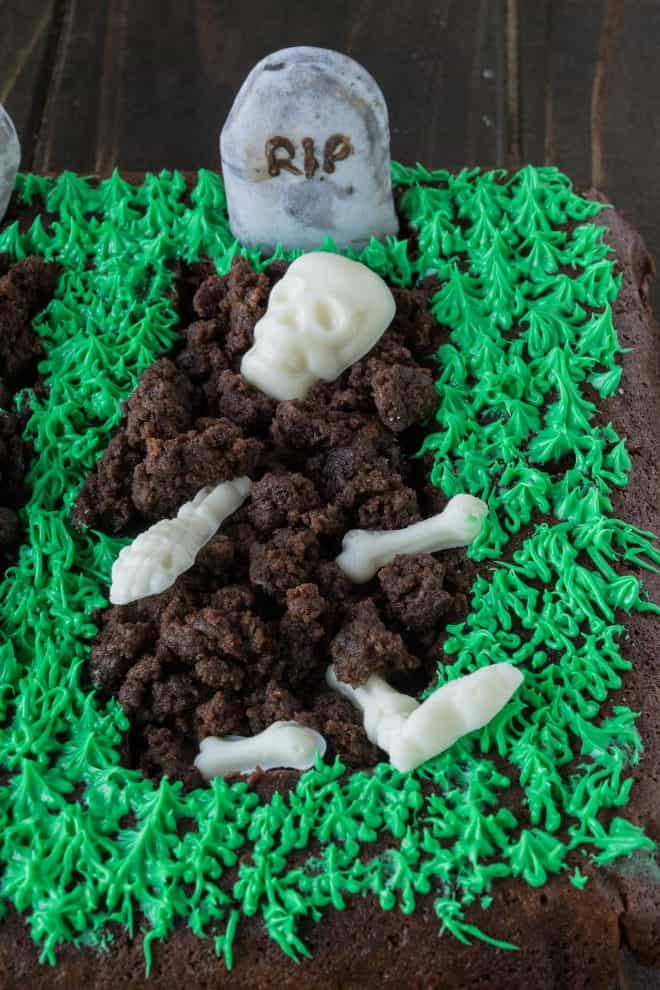 A graveyard made from brownie with a white chocolate skeleton and green frosting grass
