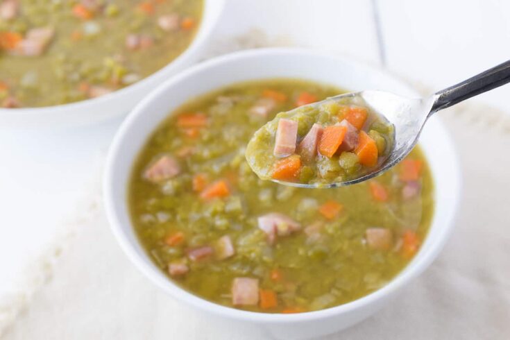 Chunks of ham, carrots split peas and potato on a spoon