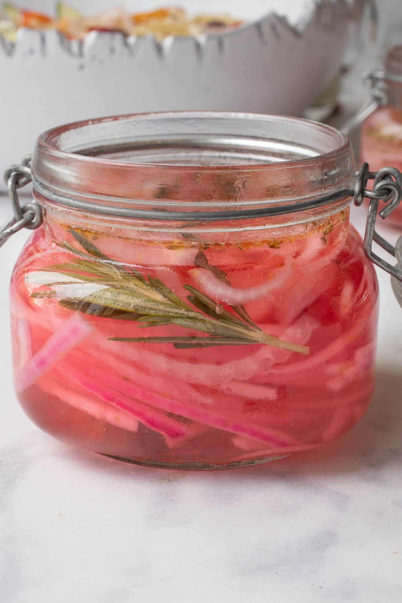 A jar of pickled red onions from the size with herbs