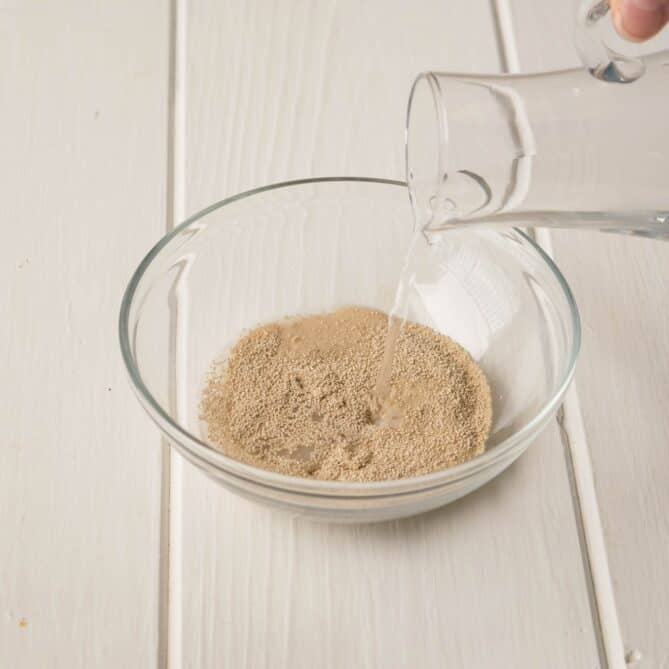 Pouring warm water over a bowl of dried yeast