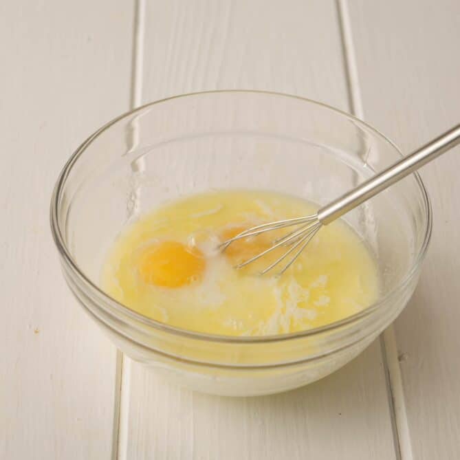 Eggs and melted butter in a bowl with a whisk